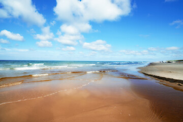 Blue, sand and water on beach in summer with calm, peace or zen outdoor for holiday, travel or vacation. Earth, nature and tide with view of ocean or sea in Denmark for climate, seashore or trip