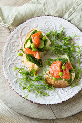 bruschetta with salmon, cucumbers and green peas on a light table