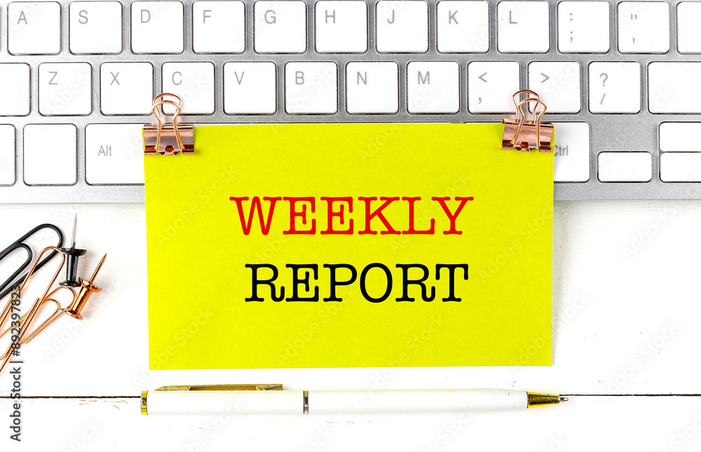 Poster weekly report text on yellow sticky on keyboard