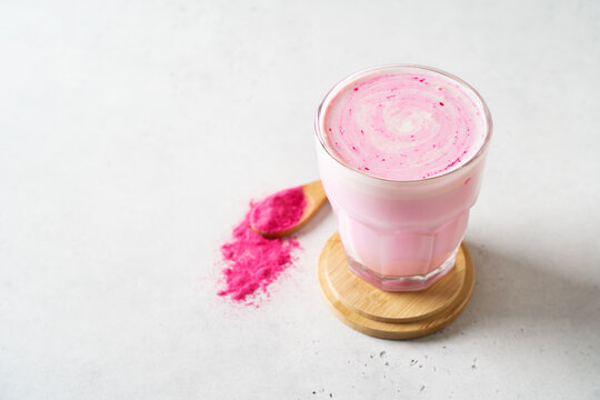 Pink matcha latte with powder on white background