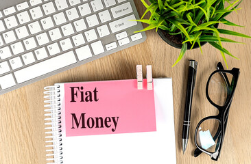 FIAT MONEY text pink sticky on notebook with keyboard, pen and glasses