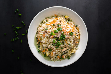 Special Mixed Fried Rice with shrimp, prawn, chicken, egg, carrot and spring onion served in plate isolated on dark background top view of chinese food