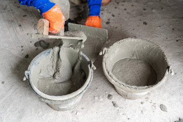 Closeup hand of a worker meticulously spreading cement plaster on a wall in a new residential...