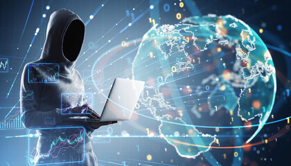 Hooded figure using a laptop with digital data graphics in the background.