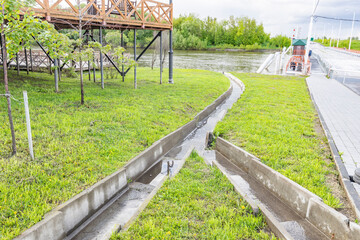 A park with a bridge over a river and a path leading to it