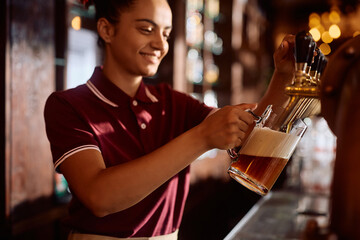 Close up of  female barista pouring draft beer in  pub.