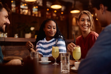 Happy woman enjoying while gathering with friends in  pub.