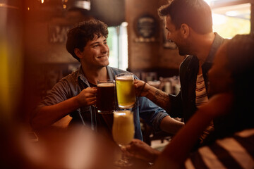 Happy men toasting with beer in  pub.