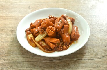 fried pork sausage with slice onion in sweet and sour sauce on plate