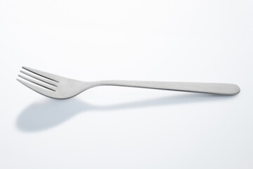 Une fourchette sur fond blanc avec une ombre de cuillère en trompe l'œil