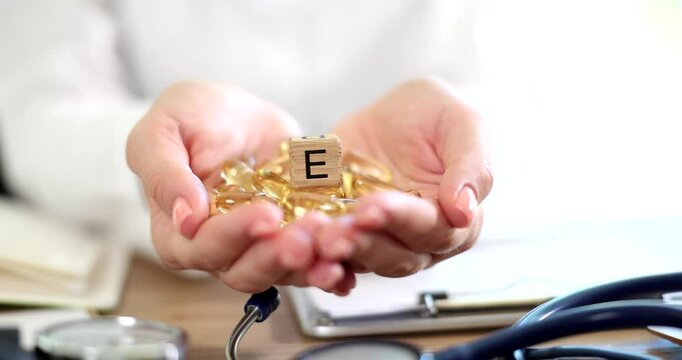Yellow gelatin capsules of vitamin e lying in hands of doctor closeup 4k movie slow motion. Prophylactic treatment with vitamins concept