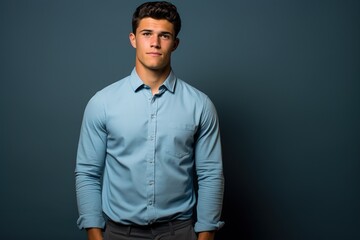 Fototapeta premium A man in a blue shirt and gray pants is standing in front of a blue wall
