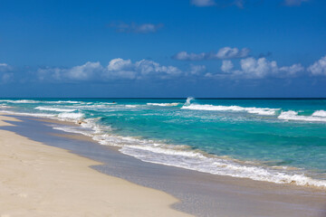Empty sea beach with white sand, view to azure waves and blue sky with cloud. Caribbean coast, background for holidays on a paradise nature