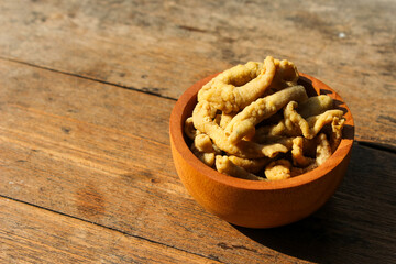 Fried chicken intestines Indonesian food is called usus goreng in a small wooden bowl with wooden background
