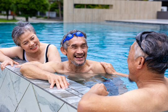 Group of senior Asian friends exercising by the swimming pool in the tropical resort hotel for summer vacation travel and happy retirement elder for healthy sport club activity wellness concept