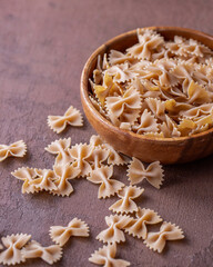 Organic Whole Wheat Farfalle Pasta in a Wooden Bowl. Bow Tie Pasta Concept. Side View.