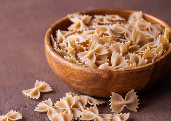 Organic Whole Wheat Farfalle Pasta in a Wooden Bowl. Bow Tie Pasta Concept. Side View.