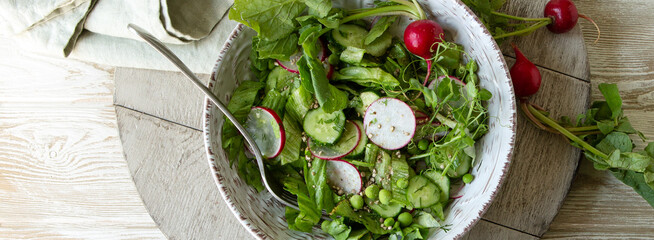 plate with spring salad with radishes, cucumbers and green peas on the table