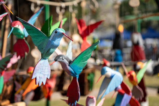 P&aacute;jaros de colores decorativos exibidos en un stand de feria de artesanos.
