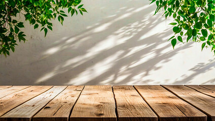 Empty wood table top against a white wall with the gentle shadow of tree leaves in the background, creating a serene and natural atmosphere perfect for product display or a tranquil setting.