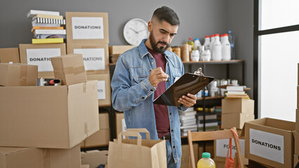 Handsome man with a beard inventorying donations in a warehouse.
