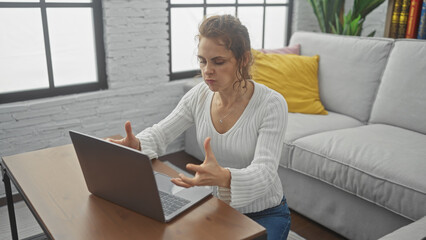 A frustrated young woman using a laptop in a modern living room.