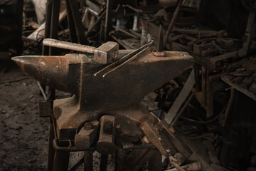 Blacksmith's anvil, hammer and forceps in old rural forge. Close-up