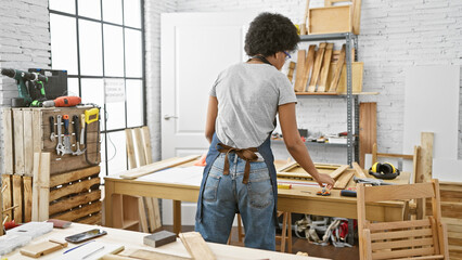 Fototapeta premium African american woman works meticulously in a well-equipped carpentry studio