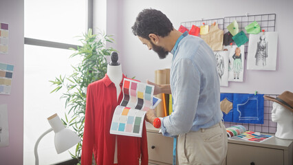 Fototapeta premium A bearded designer analyzing color palettes in a bright tailoring studio with mannequins, fabric, and sketches.