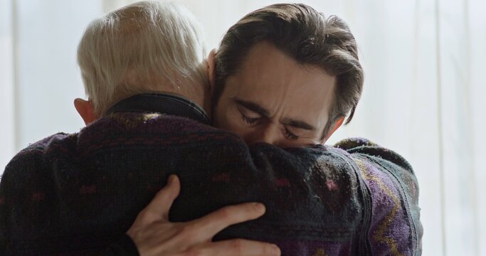 The last farewell to an adult son with an old father near the window. Strong emotional scene.