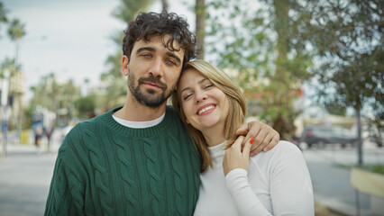 A loving couple embraces on a sunny city street, with expressions of affection and joy.