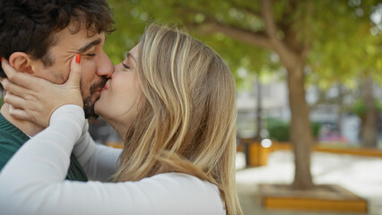 Fototapeta premium A loving couple kisses tenderly in a lush outdoor park, embodying romance and affection.