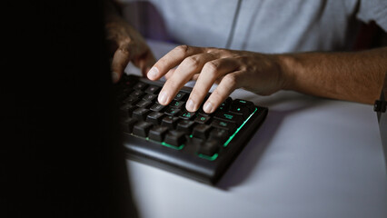 Close-up shot of a man's hands typing on a backlit mechanical keyboard in a dark room.