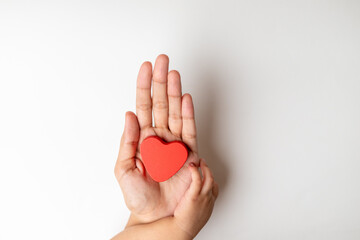 A mother and a toddler playing with heart shape red color wooden block toy, on a white background.