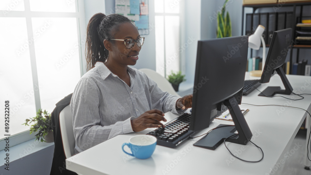 Sticker Woman working at a computer in a modern office with large windows, plants, and coffee cup on desk