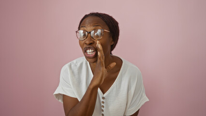 Young african american woman in white shirt and glasses shouting over isolated pink background.