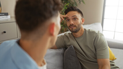 Gay couple sitting together in a cozy living room, engaging in a deep conversation with one man attentively listening to the other