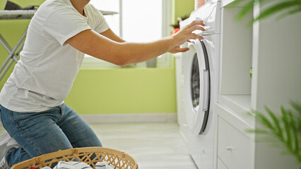 A young man doing laundry in a brightly lit home interior, evoking domestic life and routine.