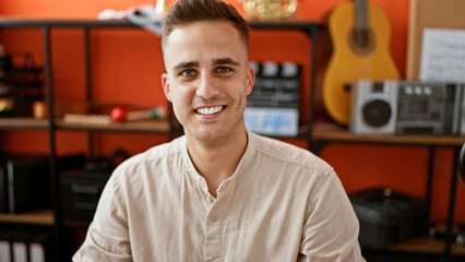 Portrait of a smiling young man indoors with music equipment in the background.