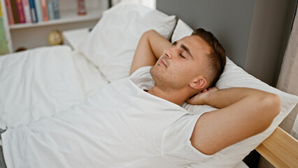 A young man relaxing in bed with eyes closed in a peaceful bedroom setting.