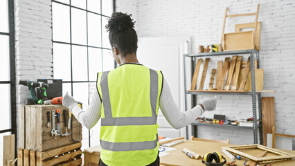 African american woman working attentively in a bright carpentry workshop, showcasing craftsmanship and skill.