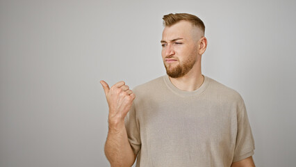 Young caucasian bearded man gesturing in frustration against an isolated white wall background,...