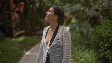 A smiling young woman enjoys a serene atmosphere at a tropical balinese resort amidst lush foliage.