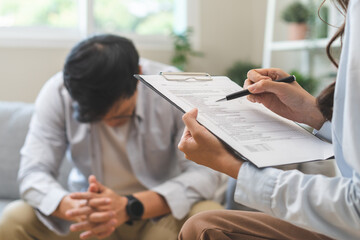 Psychology, depression. Sad, suffering asian young man, male consulting with psychologist, psychiatrist while patient counseling mental with doctor hand taking notes at clinic. Encouraging, therapy.