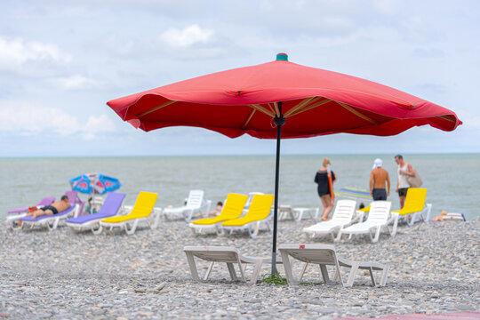 Large red beach umbrella on the pebble coast.