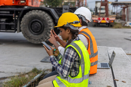 A group of civil engineers checking their smartphones for information or connecting with social media when taking a break at a construction site