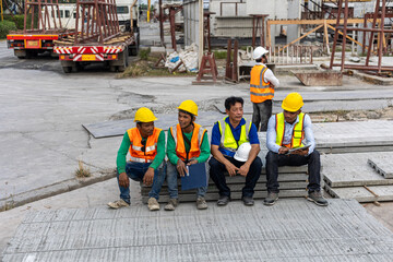 A team of constructors or engineers from different ethnicities work together in a precast factory for their production. A group of factory workers take a break having conversation together.