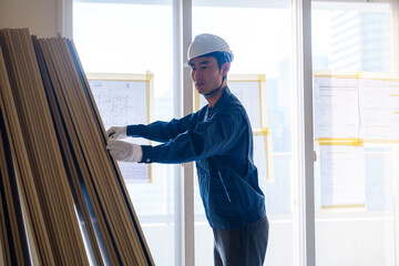 リフォーム工事の現場で石膏ボードを運ぶ職人