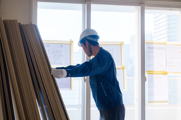 リフォーム工事の現場で石膏ボードを運ぶ職人