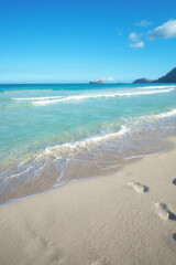 Blue sky, ocean and footprints in sand for travel, vacation or holiday in summer by coastal island. Walk mark, steps and sea waves on LaniKai beach for tropical weekend trip at destination in Hawaii.